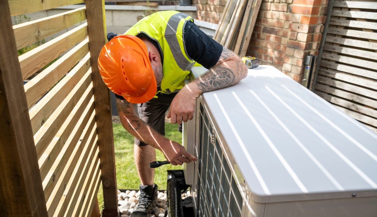 An installer inspecting an air source heat pump